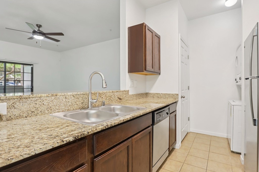 A kitchen with a sink, refrigerator, and cabinets.