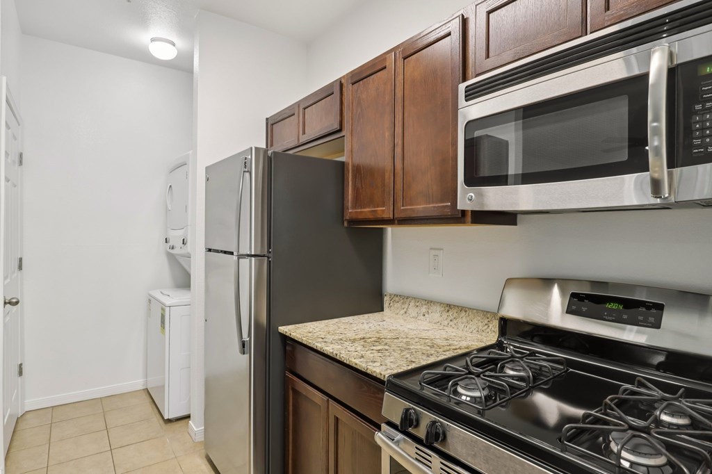 A kitchen with a black refrigerator, stove, and microwave.