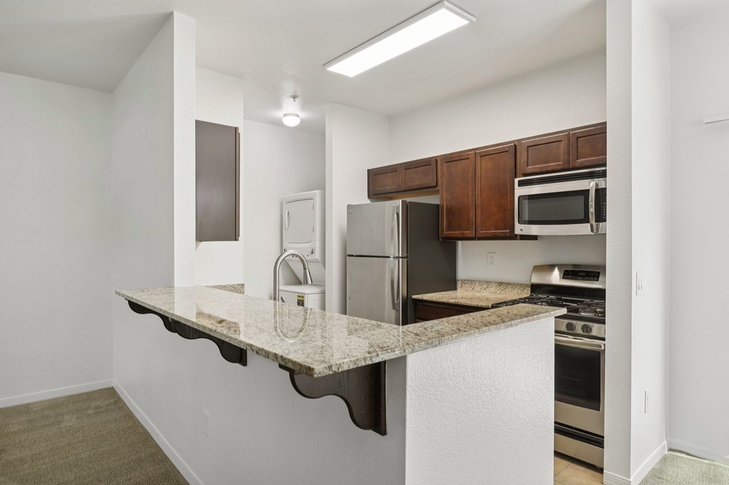 A kitchen with a white counter top and stainless steel appliances.