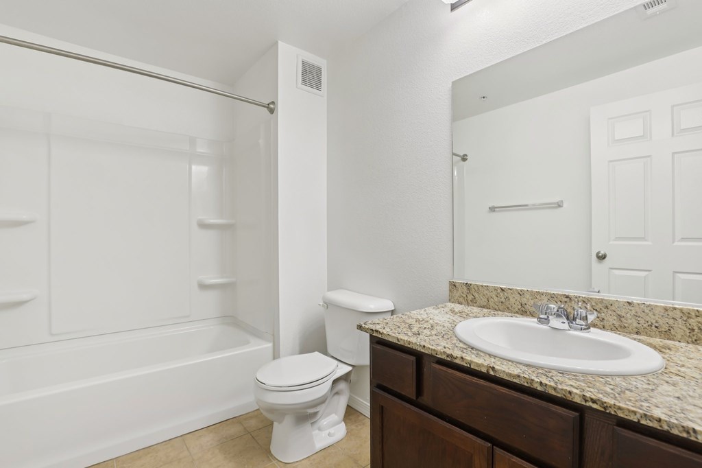 A white toilet sits in a bathroom next to a sink.