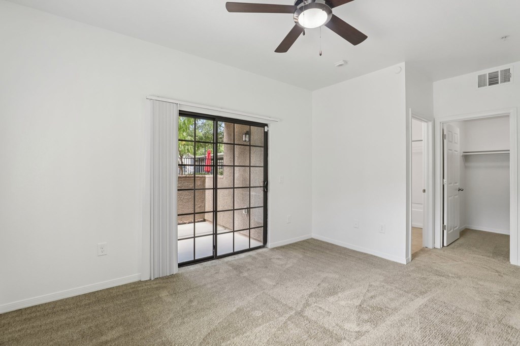 A room with a ceiling fan and a sliding glass door leading outside.
