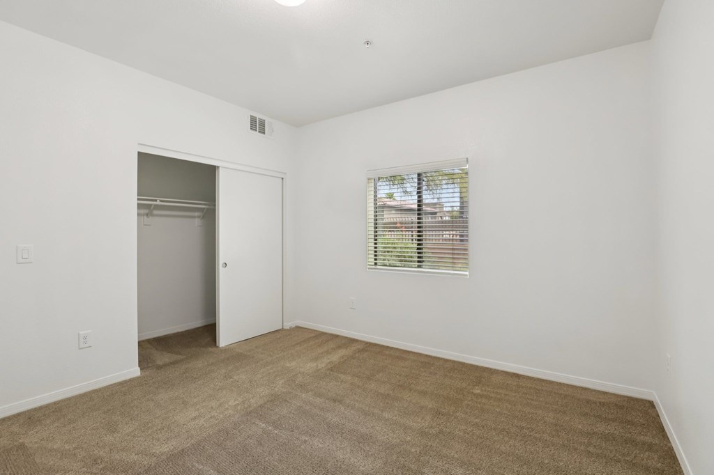 A room with a carpeted floor and a window with blinds.
