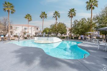 A swimming pool surrounded by palm trees and lounge chairs.