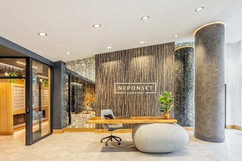 A modern office space with a wooden reception desk and a large stone pillar.