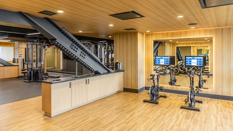 A gym with a wooden floor, a row of exercise bikes, and a stair lift.