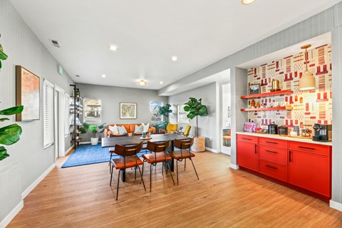 A kitchen with red cabinets and a dining table with chairs.