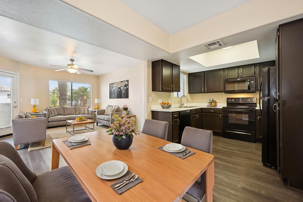 A modern kitchen with dark brown cabinets and a wooden dining table set for two.