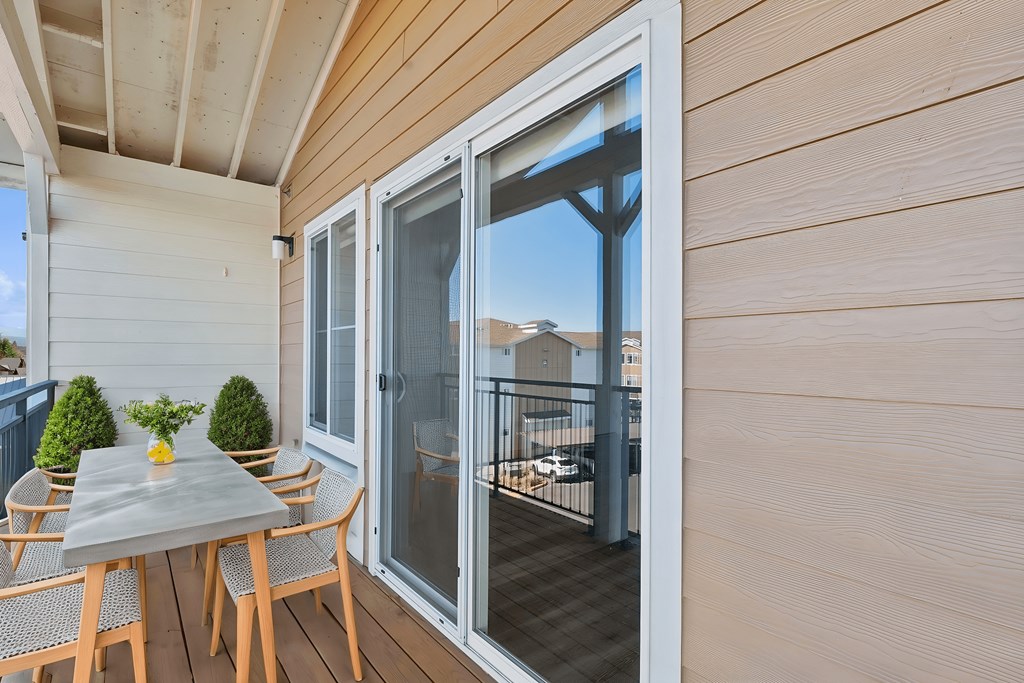 A table with chairs is on a balcony with a view of the outside.