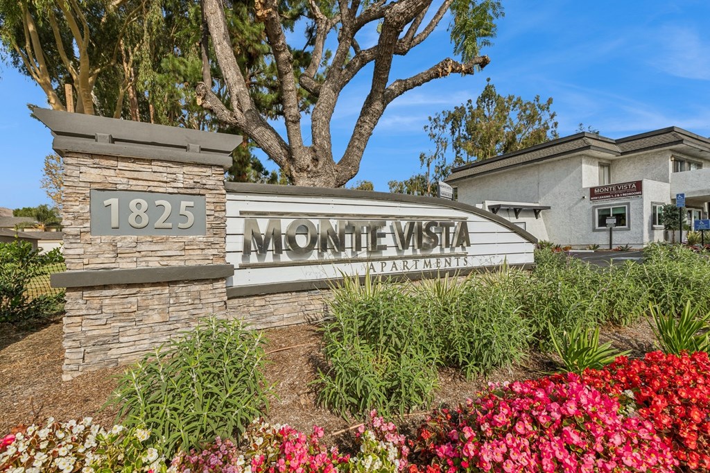 The sign for Monte Vista Apartments is surrounded by flowers and greenery.