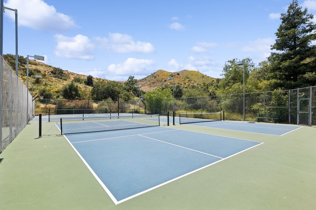 a tennis court with a fence and mountains in the background