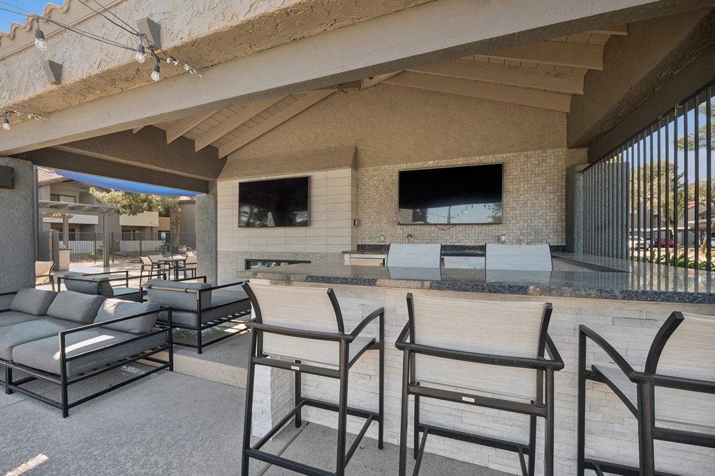 a patio with a bar and chairs and a television