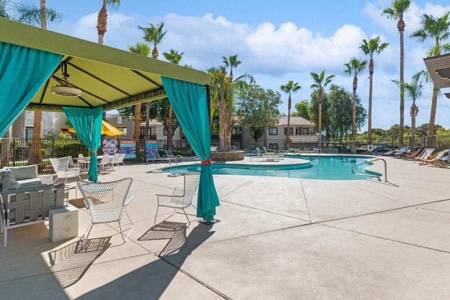 a swimming pool with chaise lounges and palm trees in the background