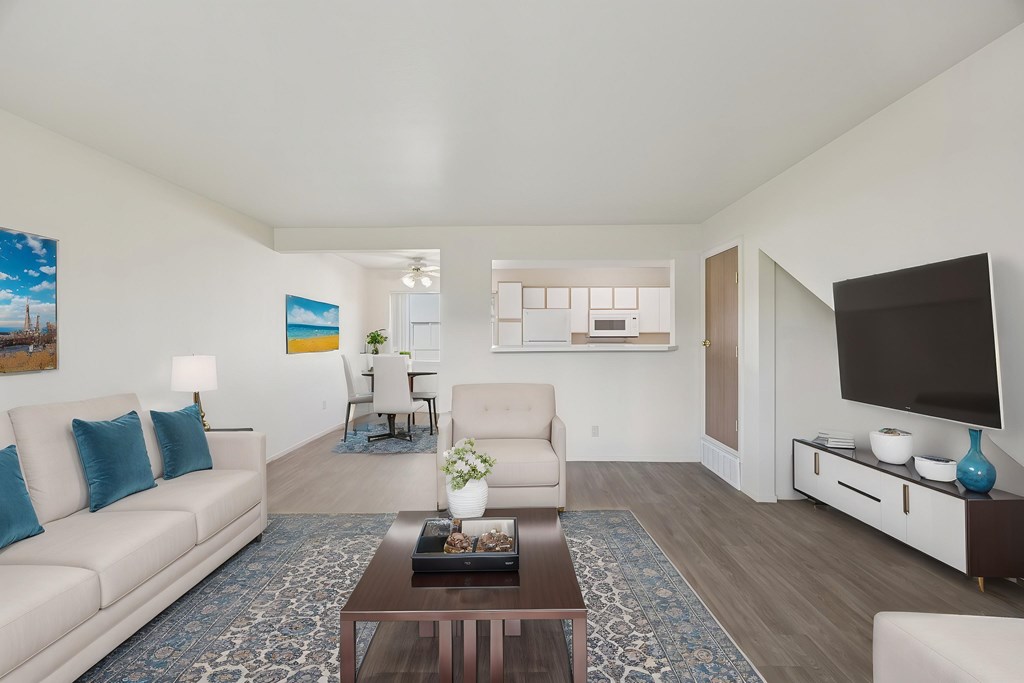 A living room with a white couch, a coffee table, and a television.
