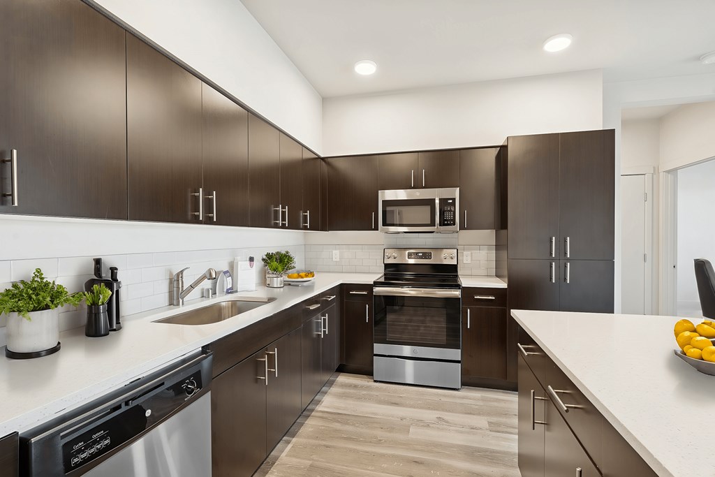 A modern kitchen with dark brown cabinets and stainless steel appliances.