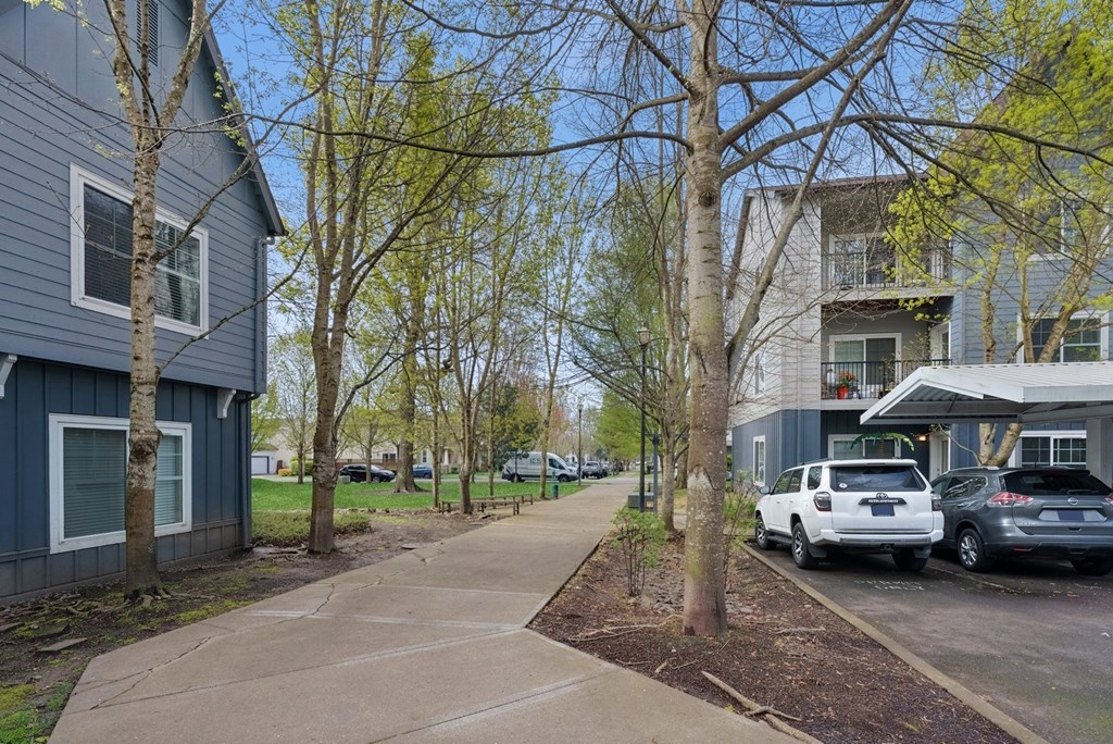 A residential area with a sidewalk and parked cars.