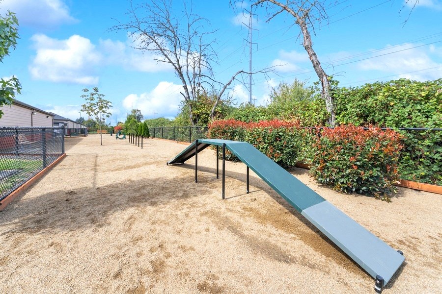 a blue park bench in a fenced in area with bushes and trees