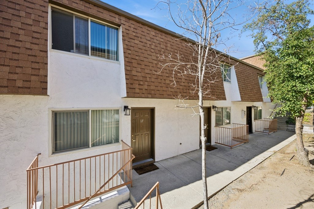 A brown and white building with a tree in front.