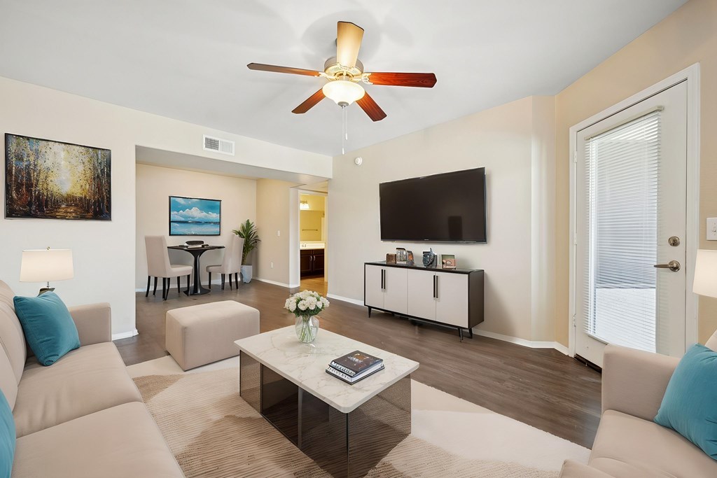 A living room with a beige couch, a coffee table, and a ceiling fan.