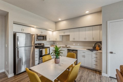 a kitchen and dining room with white cabinets and stainless steel appliances