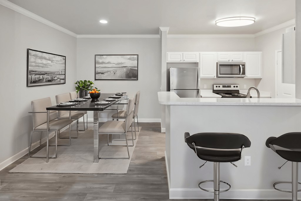 A kitchen with a bar stool and a dining table.
