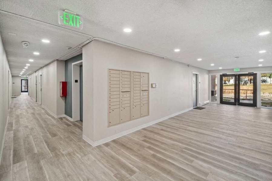 the upstairs hallway of a building with mailboxes and a exit sign
