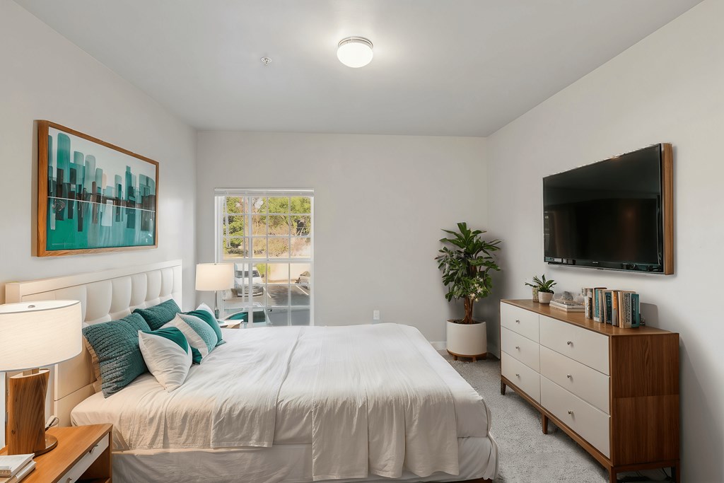 A bedroom with a bed, nightstand, and a painting on the wall.