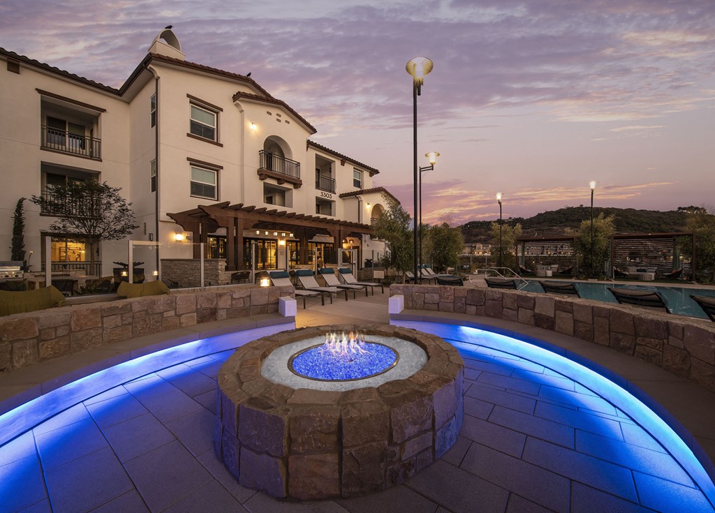 an outdoor fire pit at night with a building in the background