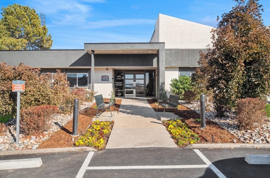 the front of a building with a walkway and benches in front of it