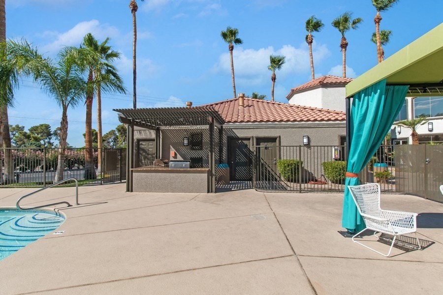 a backyard with a pool and a gazebo with palm trees in the background