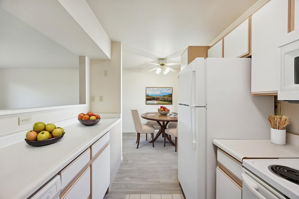 A kitchen with white appliances and a table with chairs.