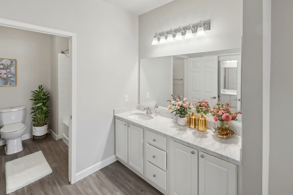 A white bathroom with a toilet, sink, and mirror.