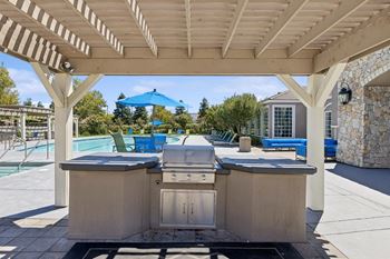 the outdoor kitchen is under a covered pavilion next to a pool