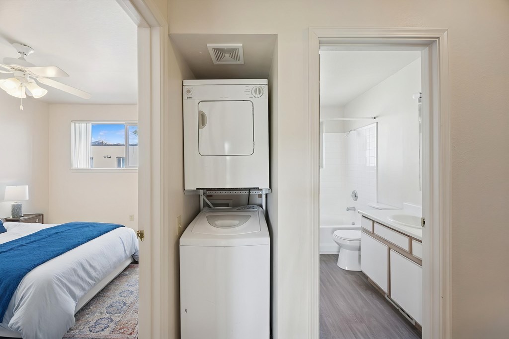 A bedroom with a bed, a washing machine, and a bathroom.