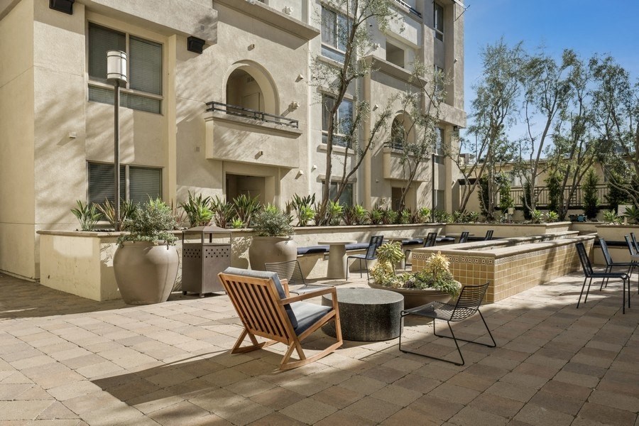 a patio with chairs and tables in front of a building