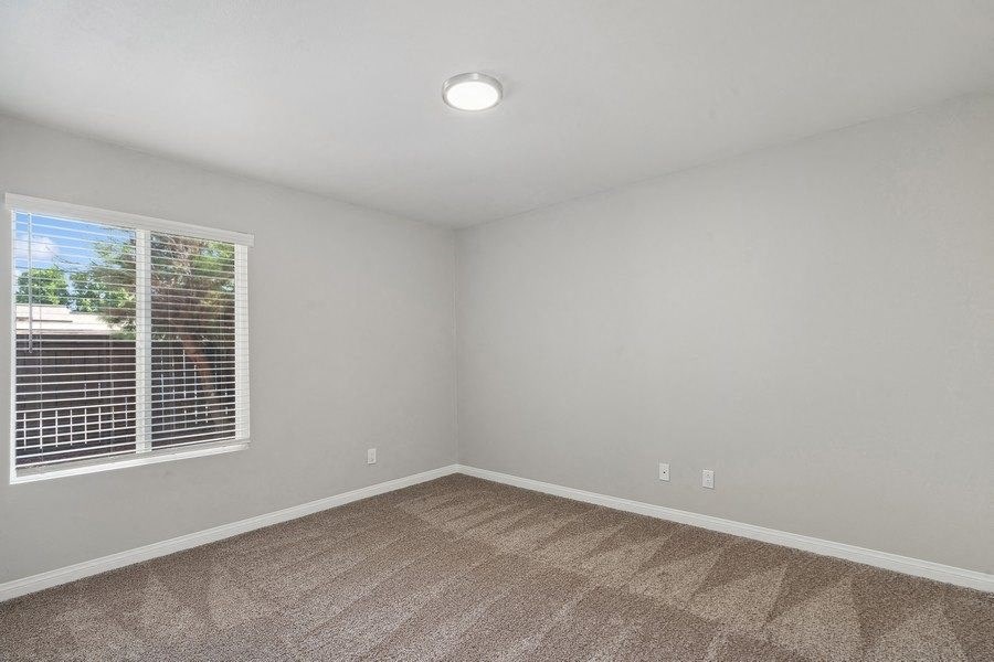 an empty bedroom with a large window and carpeting