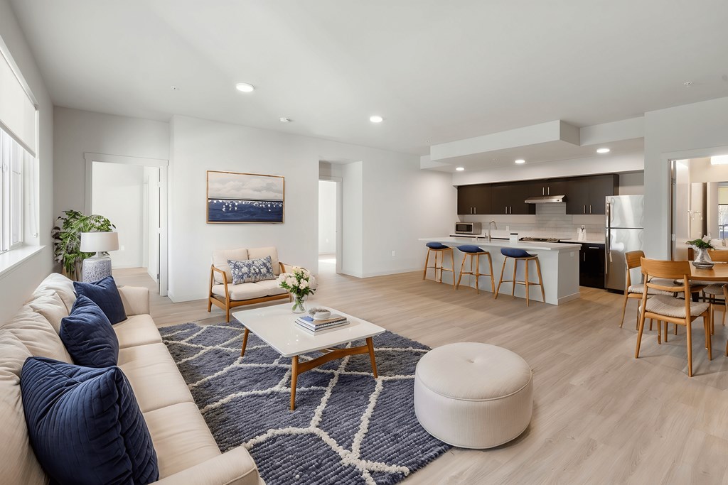 A modern living room with a large sofa, a coffee table, and a dining area.