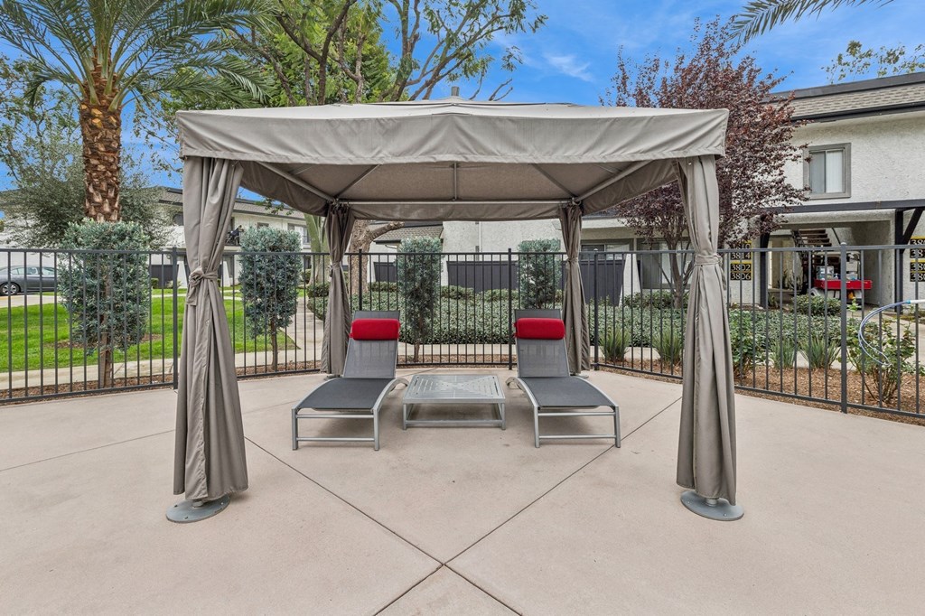 A patio with a canopy and two chairs.