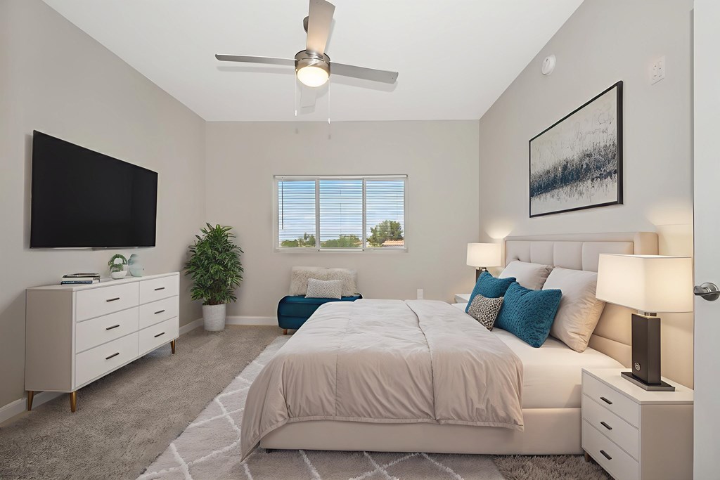A bedroom with a large bed, a flat screen TV, and a ceiling fan.