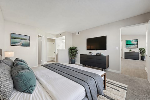 A bedroom with a large bed and a flat screen TV mounted on the wall.