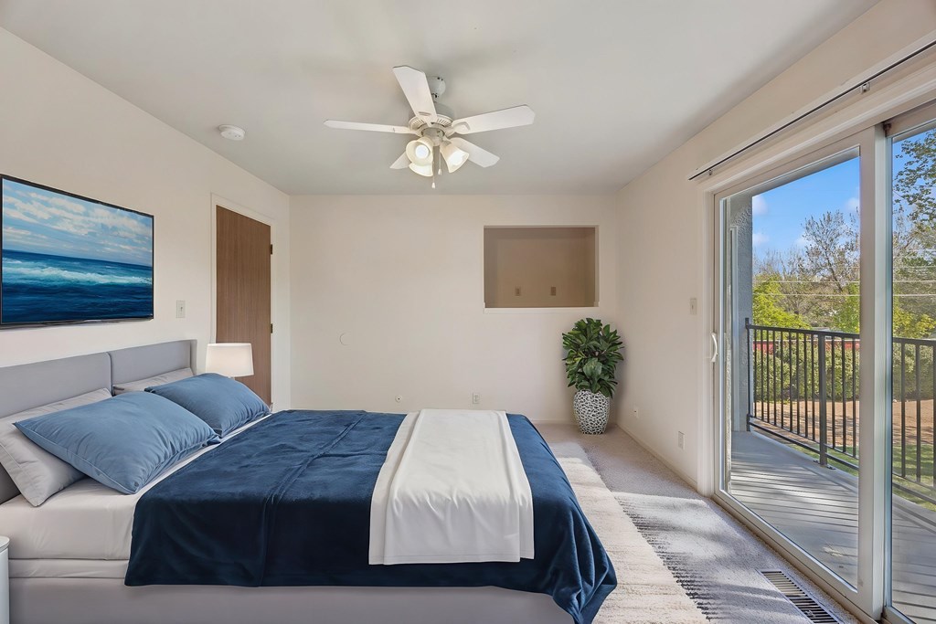 A bedroom with a bed, a ceiling fan, and a painting on the wall.