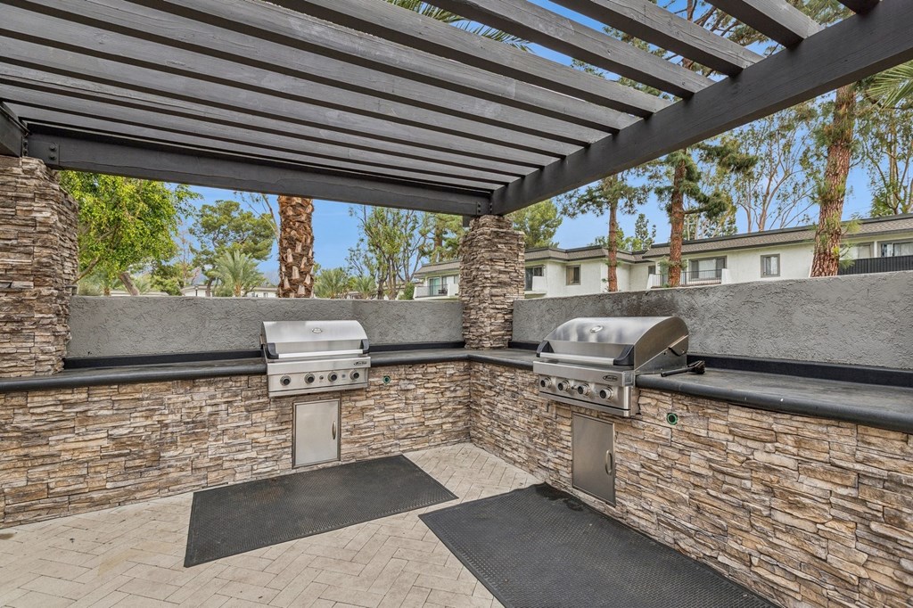 A patio with a grill and a stone wall.