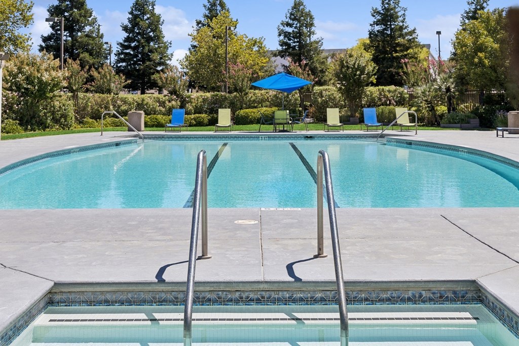 a swimming pool with a blue umbrella and chairs around it