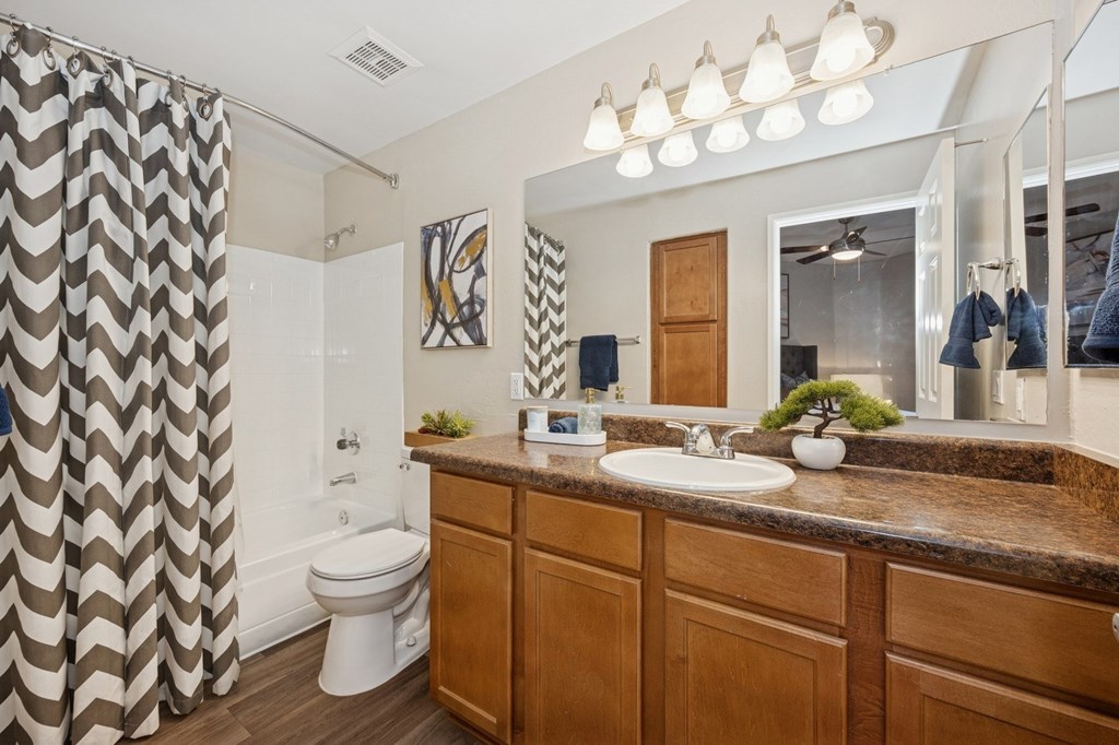A bathroom with a brown counter top and a white toilet.