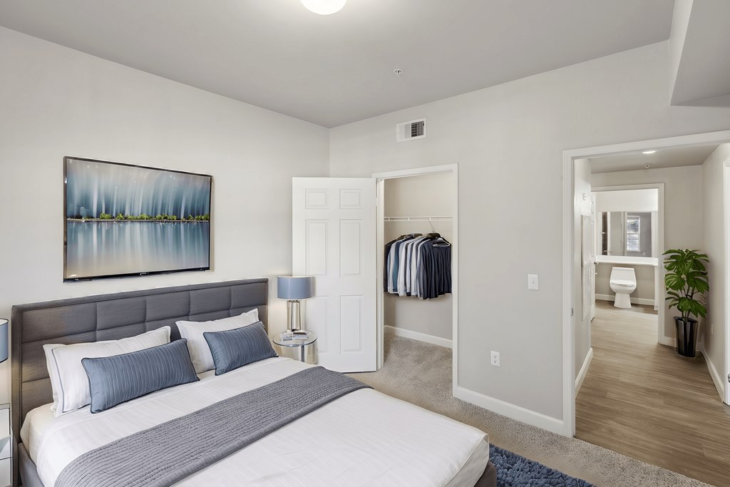 A bedroom with a large bed and a painting on the wall.