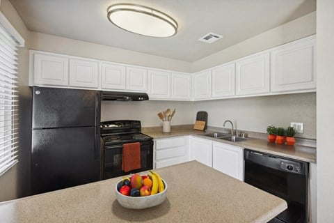 a kitchen with black appliances and a bowl of fruit