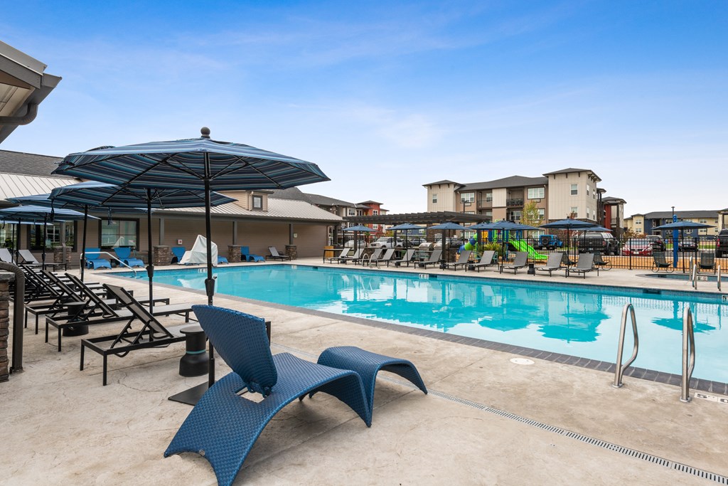 a swimming pool with chairs and umbrellas at the resort on a sunny day