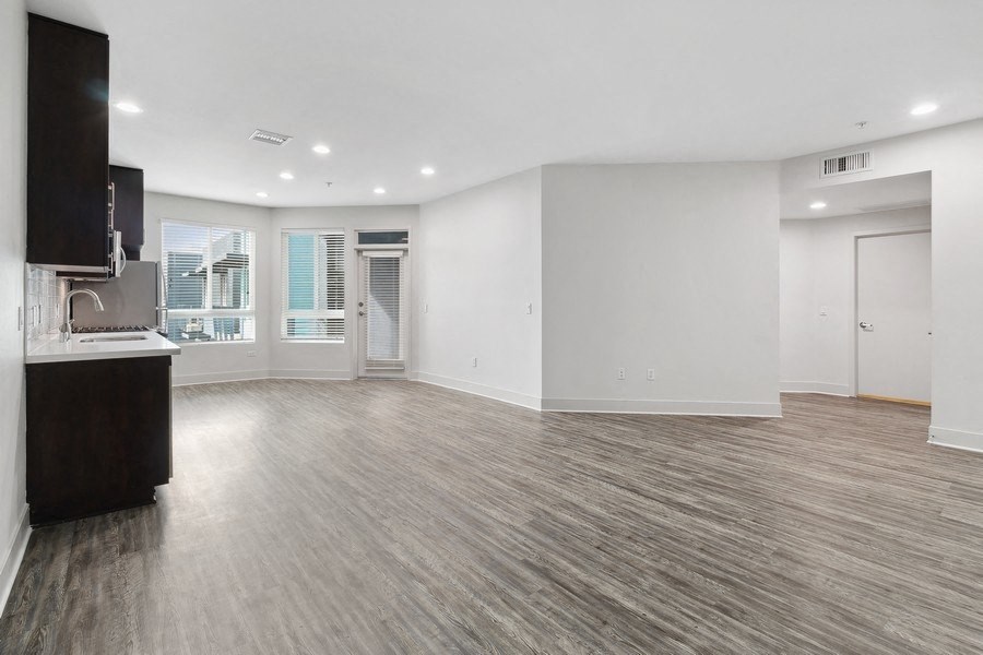 an empty living room with a kitchen and a sink
