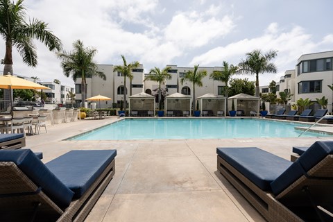A pool surrounded by lounge chairs and umbrellas.