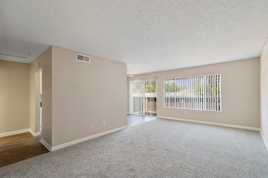 the spacious living room and dining room of an empty apartment