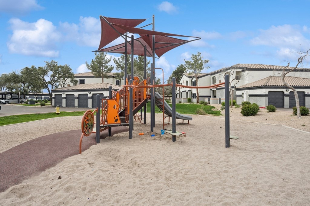 a playground with an orange swing set in front of a building